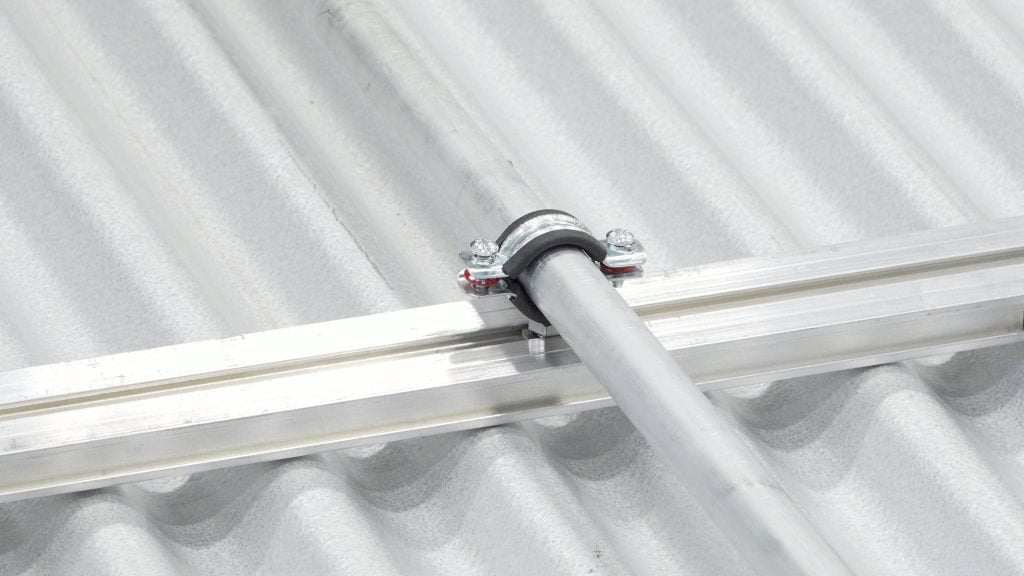 S-5 CanDuit pipe and conduit securement clamp installed on a Butler metal roof showing organized clean pipe management without wood blocks cinderblocks or penetrating fasteners