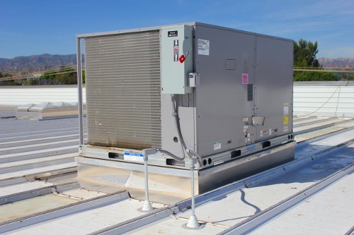 Commercial rooftop HVAC equipment mounted on Butler roof curbs over a standing seam metal building roof