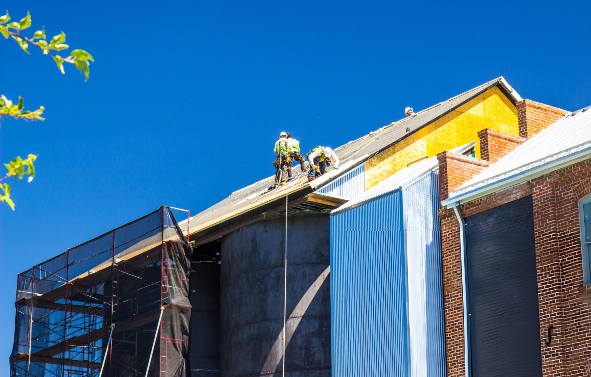 Workers On Roof Over Vintage Storage Tanks